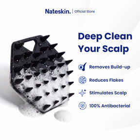 Nateskin black silicone scalp scrubber with spiky bristles, shown covered in white foam on a clean white background with promotional text listing benefits like removing build-up, reducing flakes, stimulating scalp, and 100% antibacterial.